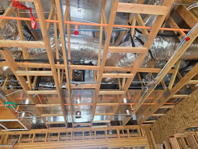 Insulated flexible HVAC ducts running above open ceiling framing at a new home under construction in El Dorado Hills, CA