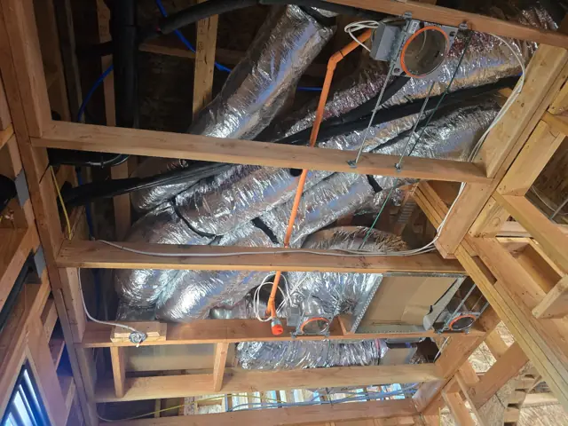 Several insulated HVAC duct runs and a sheet-metal duct box between ceiling joists at an El Dorado Hills home before drywall