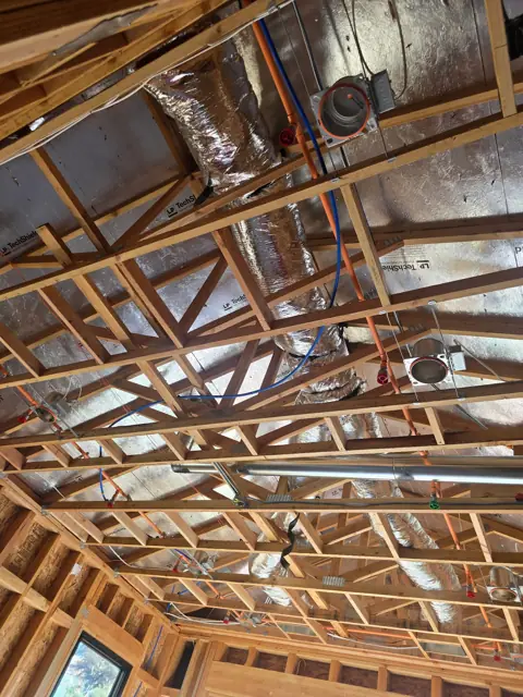 Insulated HVAC duct routed through roof trusses under a radiant-barrier roof deck in an El Dorado Hills new construction home